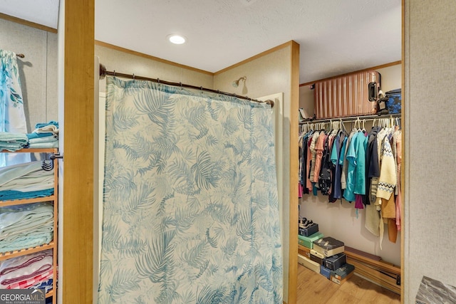 bathroom featuring hardwood / wood-style floors, ornamental molding, and a shower with shower curtain