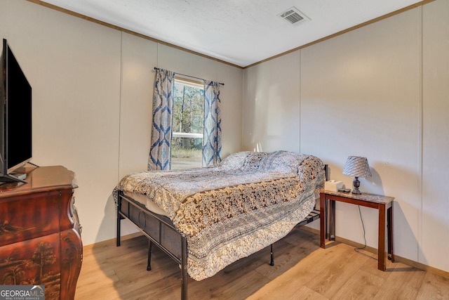 bedroom featuring light hardwood / wood-style flooring and ornamental molding