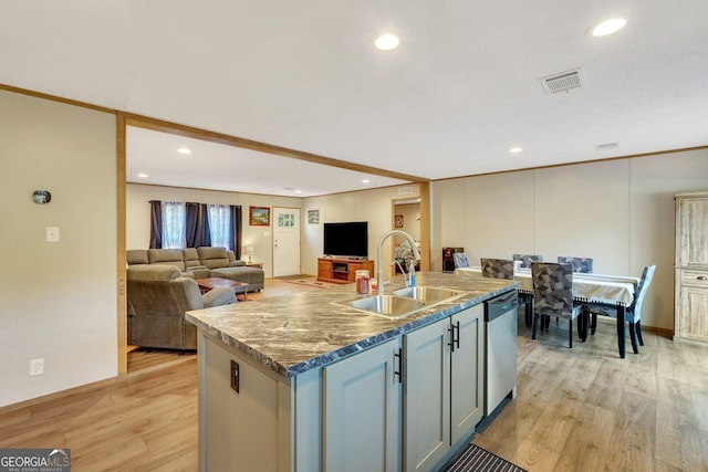 kitchen with light wood-type flooring, stainless steel dishwasher, gray cabinetry, sink, and an island with sink