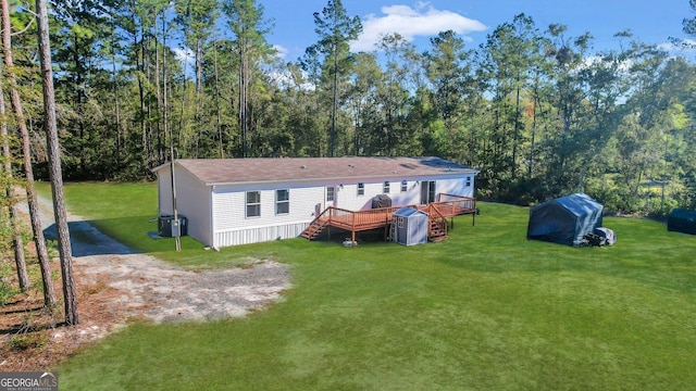 rear view of house featuring cooling unit, a deck, and a yard