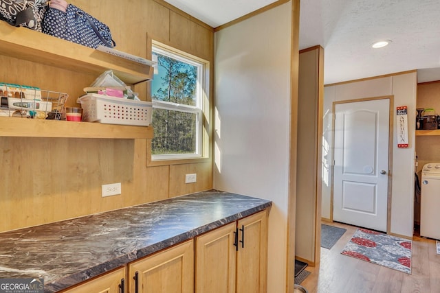 kitchen with washer / dryer, a textured ceiling, light hardwood / wood-style flooring, and wooden walls