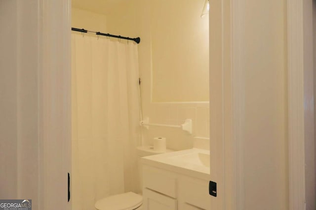 bathroom featuring vanity, toilet, backsplash, and walk in shower