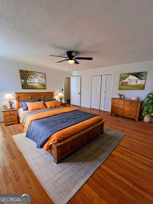 bedroom featuring ceiling fan, a closet, a textured ceiling, and light wood-type flooring