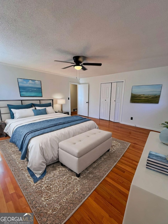 bedroom featuring a closet, ceiling fan, hardwood / wood-style floors, and a textured ceiling