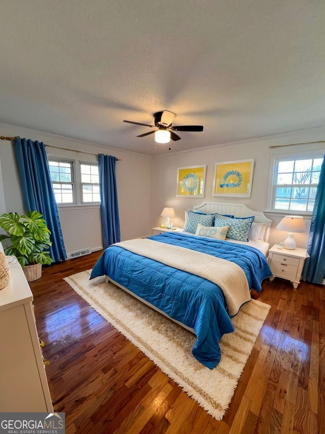 bedroom with ceiling fan, dark hardwood / wood-style floors, a textured ceiling, and multiple windows