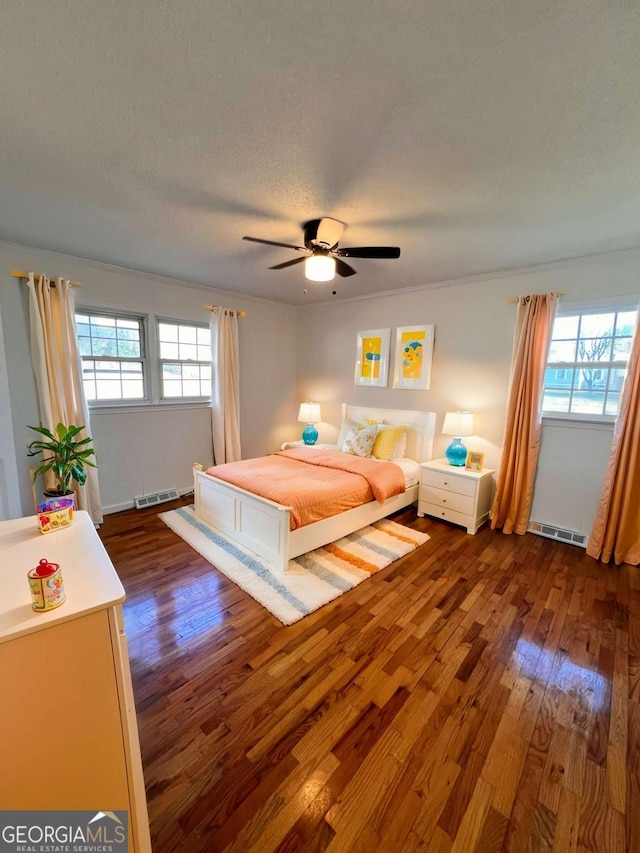 bedroom with multiple windows, ceiling fan, dark hardwood / wood-style flooring, and a textured ceiling