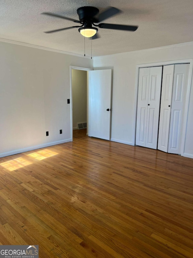 unfurnished bedroom featuring hardwood / wood-style flooring, ceiling fan, ornamental molding, and a textured ceiling