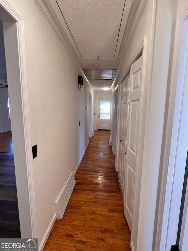 corridor featuring a textured ceiling and dark wood-type flooring