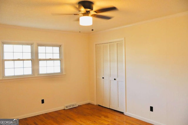 unfurnished bedroom featuring wood-type flooring, a closet, ceiling fan, and crown molding