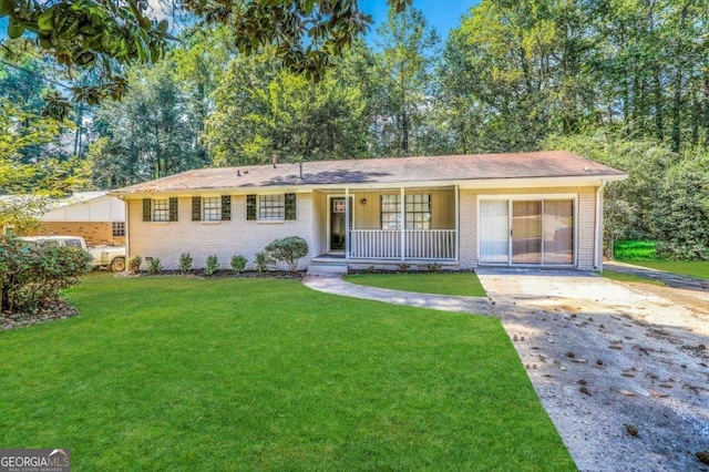 ranch-style house featuring covered porch and a front yard