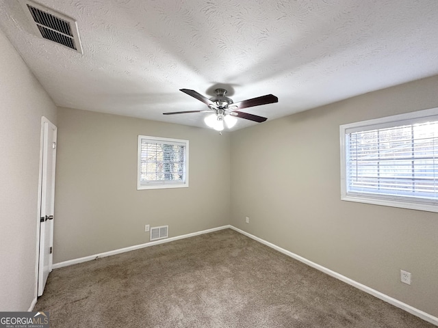 carpeted spare room featuring ceiling fan and a textured ceiling