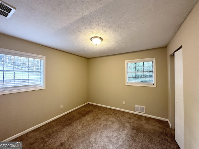 carpeted spare room featuring a textured ceiling