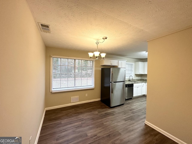 kitchen with stainless steel appliances, sink, a notable chandelier, white cabinetry, and hanging light fixtures