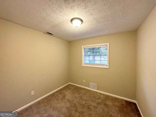 carpeted empty room featuring a textured ceiling