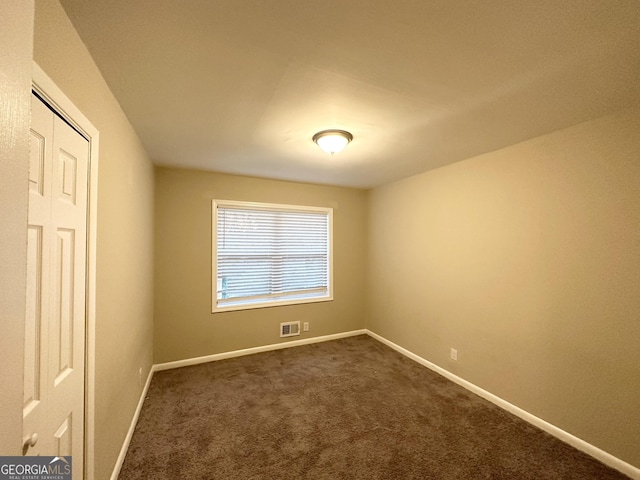 unfurnished room with dark colored carpet