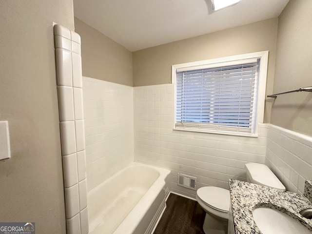 bathroom featuring hardwood / wood-style floors, vanity, a bath, toilet, and tile walls