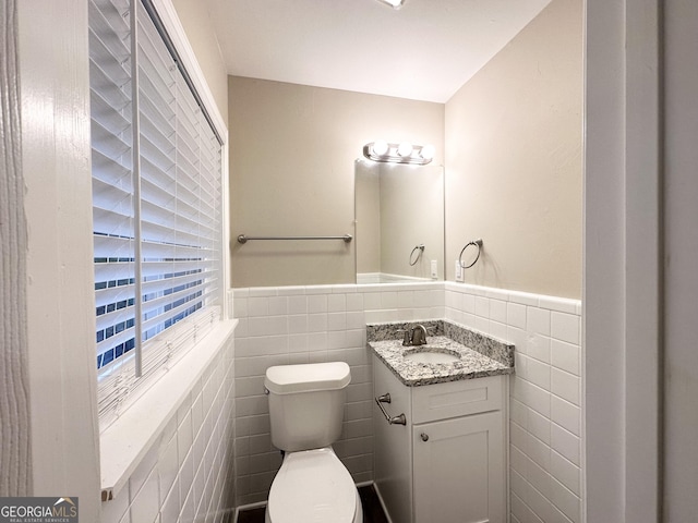 bathroom with vanity, toilet, and tile walls