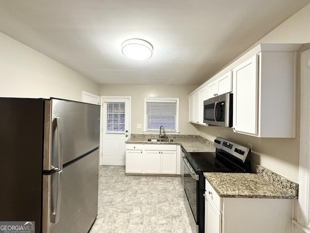 kitchen featuring white cabinets, appliances with stainless steel finishes, stone counters, and sink