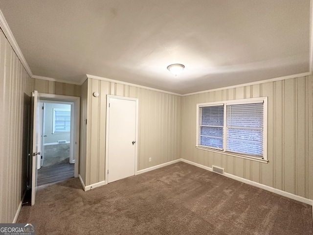 unfurnished bedroom with dark carpet, ornamental molding, and a closet