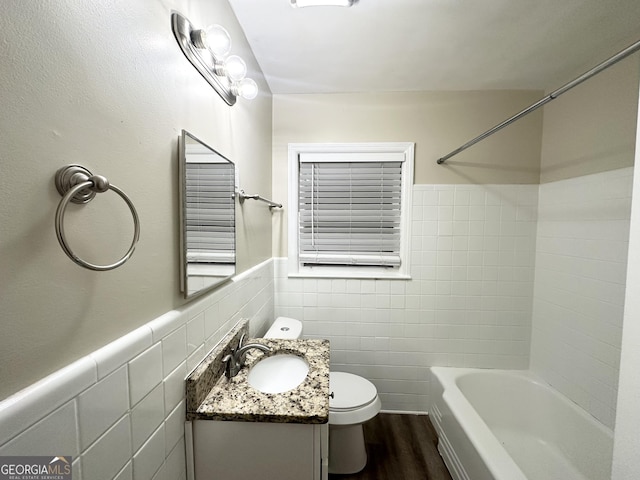 full bathroom featuring wood-type flooring,  shower combination, toilet, vanity, and tile walls