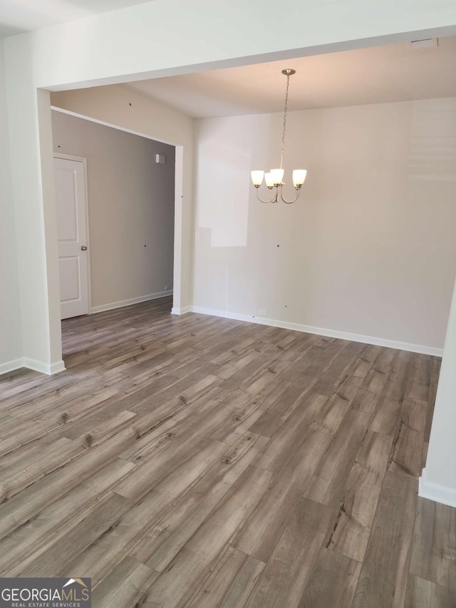 empty room featuring a chandelier and wood-type flooring