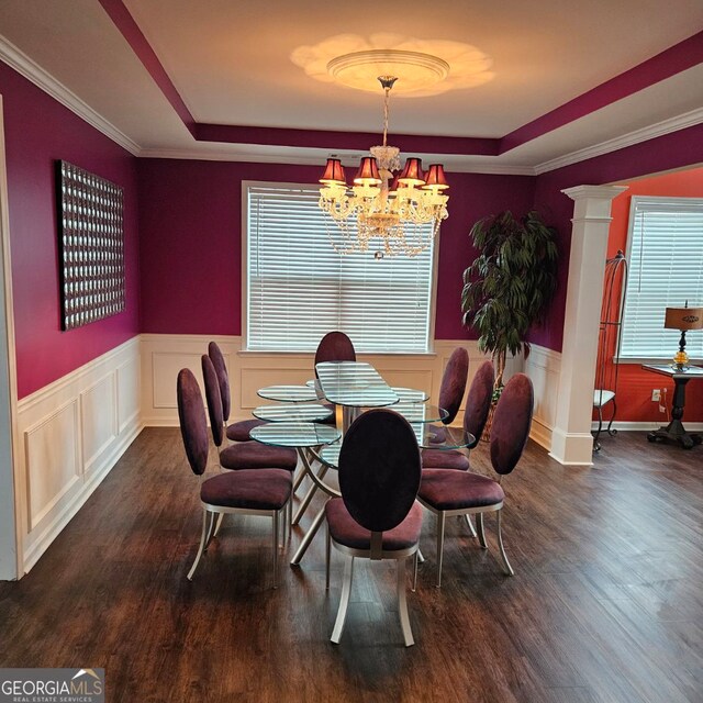 dining space with a wealth of natural light, dark wood-type flooring, a raised ceiling, a chandelier, and ornamental molding