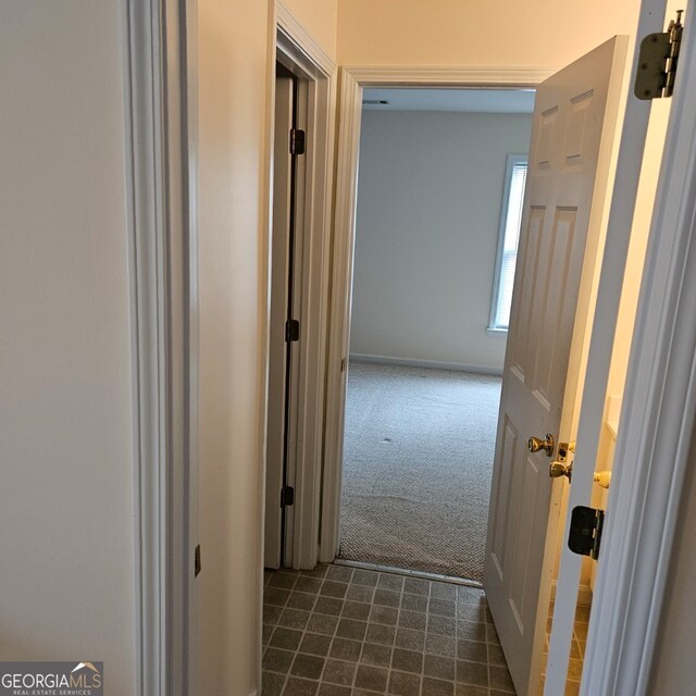 hall featuring dark colored carpet