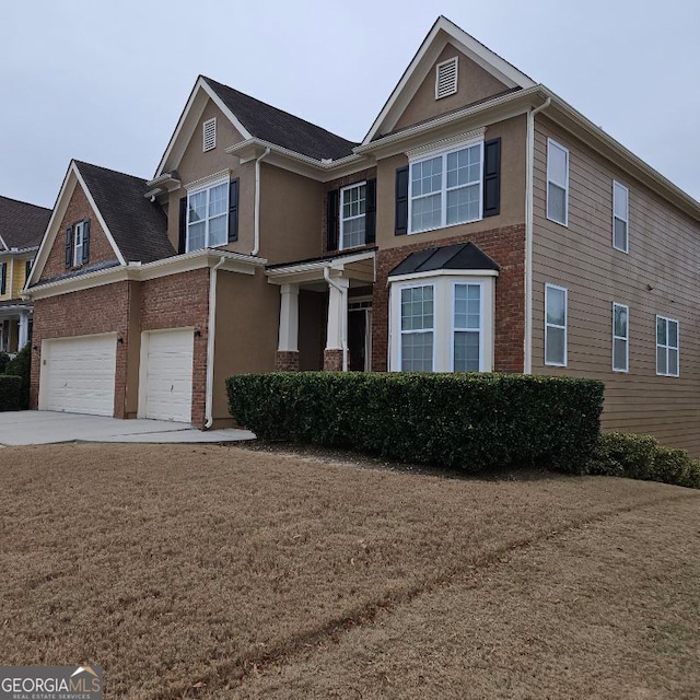 view of front of property with brick siding, a garage, driveway, and stucco siding