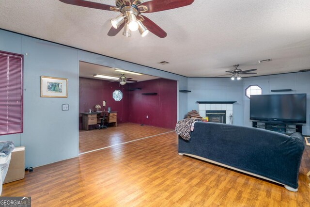 living room with a fireplace, wood-type flooring, and a textured ceiling