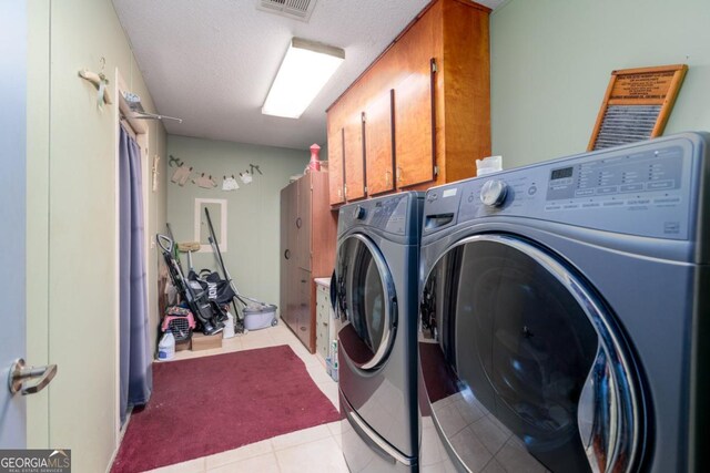 clothes washing area featuring cabinets, light tile patterned floors, a textured ceiling, and separate washer and dryer