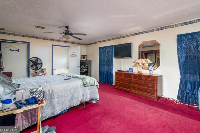 bedroom with ceiling fan, carpet floors, and a textured ceiling