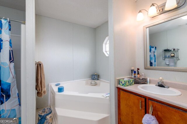 bathroom featuring vanity, a bath, and a textured ceiling