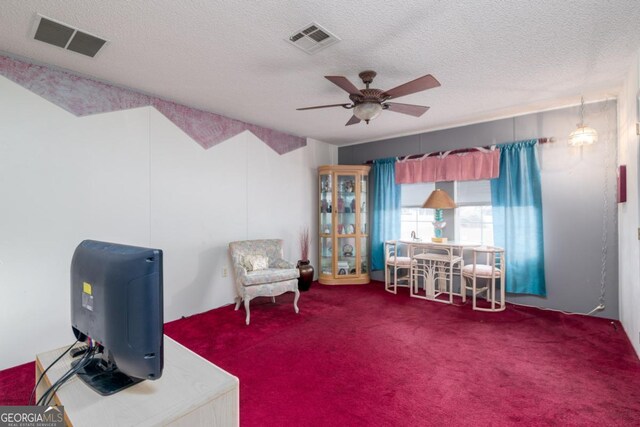 sitting room with ceiling fan, carpet floors, and a textured ceiling