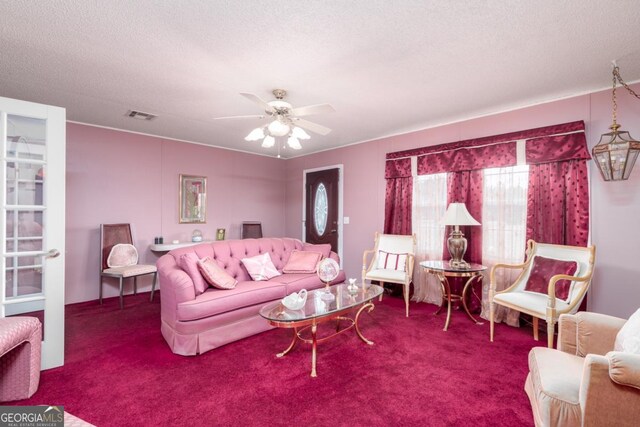 living room featuring a textured ceiling, carpet floors, and ceiling fan