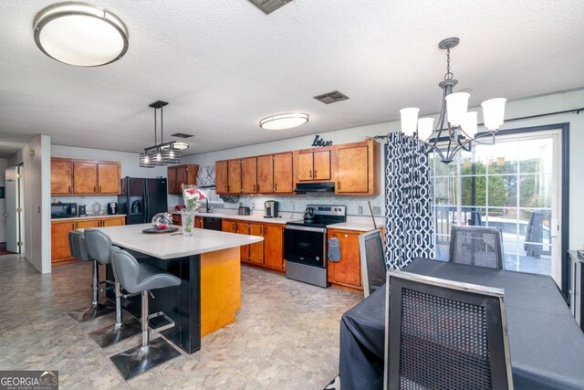 kitchen with a center island, exhaust hood, black appliances, hanging light fixtures, and a kitchen bar