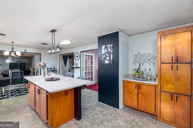 kitchen featuring a chandelier, a textured ceiling, a center island, and decorative light fixtures