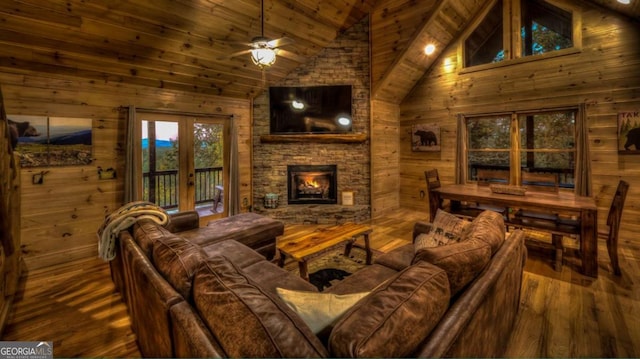 living room with ceiling fan, french doors, wooden walls, and hardwood / wood-style flooring