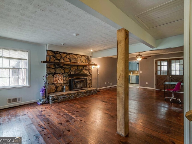 unfurnished living room with ceiling fan, dark wood-type flooring, a wealth of natural light, and a textured ceiling