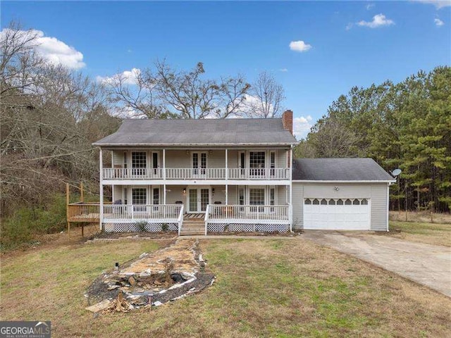 view of front of home featuring covered porch, a garage, a front yard, and french doors