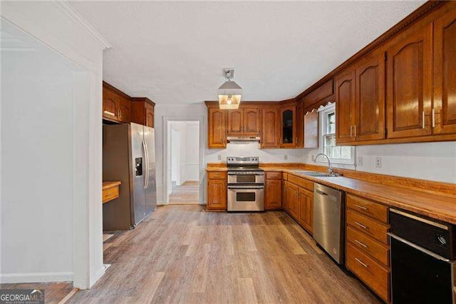 kitchen with crown molding, light wood-type flooring, sink, and appliances with stainless steel finishes