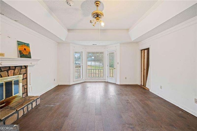 unfurnished living room featuring ceiling fan, dark wood-type flooring, crown molding, a tray ceiling, and a fireplace