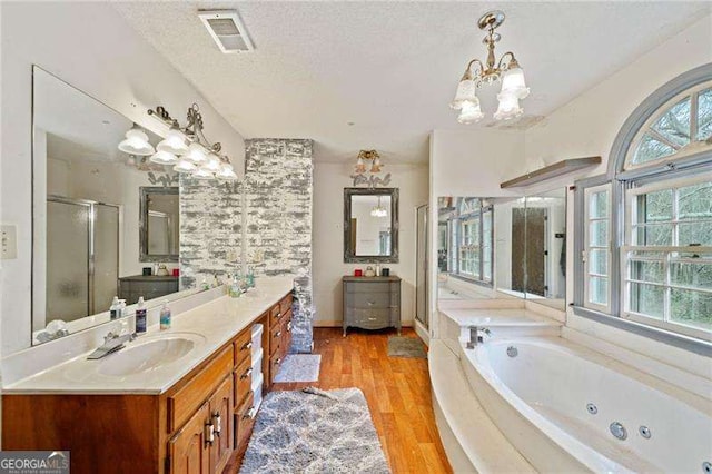 bathroom featuring vanity, a textured ceiling, shower with separate bathtub, an inviting chandelier, and hardwood / wood-style floors