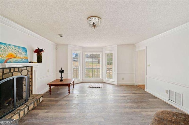 unfurnished living room featuring a textured ceiling, wood-type flooring, ornamental molding, and a fireplace