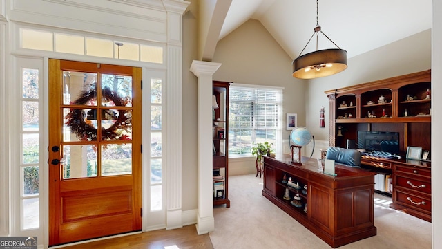 carpeted office space with decorative columns and lofted ceiling