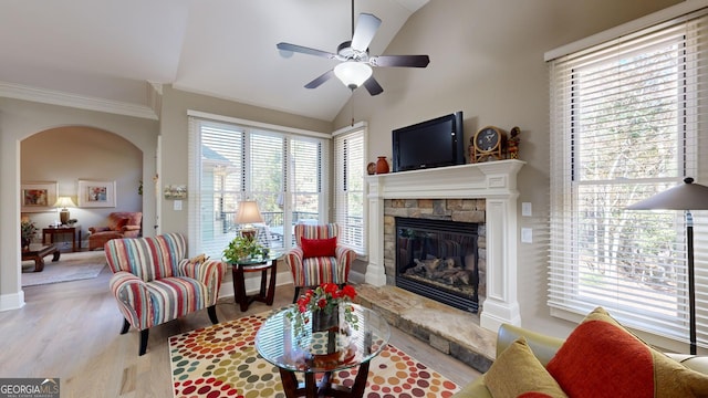 living room featuring ceiling fan, light wood-type flooring, lofted ceiling, and a fireplace