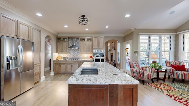 kitchen featuring backsplash, wall chimney exhaust hood, stainless steel appliances, and an island with sink