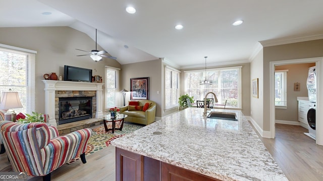 kitchen with sink, a healthy amount of sunlight, light hardwood / wood-style flooring, decorative light fixtures, and a fireplace