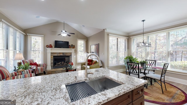 kitchen featuring sink, hardwood / wood-style flooring, light stone countertops, a fireplace, and decorative light fixtures