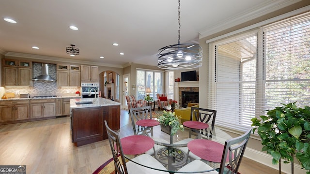 dining space featuring a chandelier, sink, ornamental molding, and light wood-type flooring