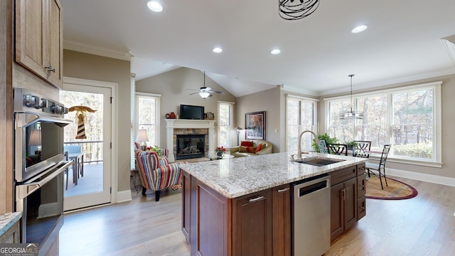 kitchen with sink, stainless steel appliances, light hardwood / wood-style floors, a center island with sink, and ornamental molding